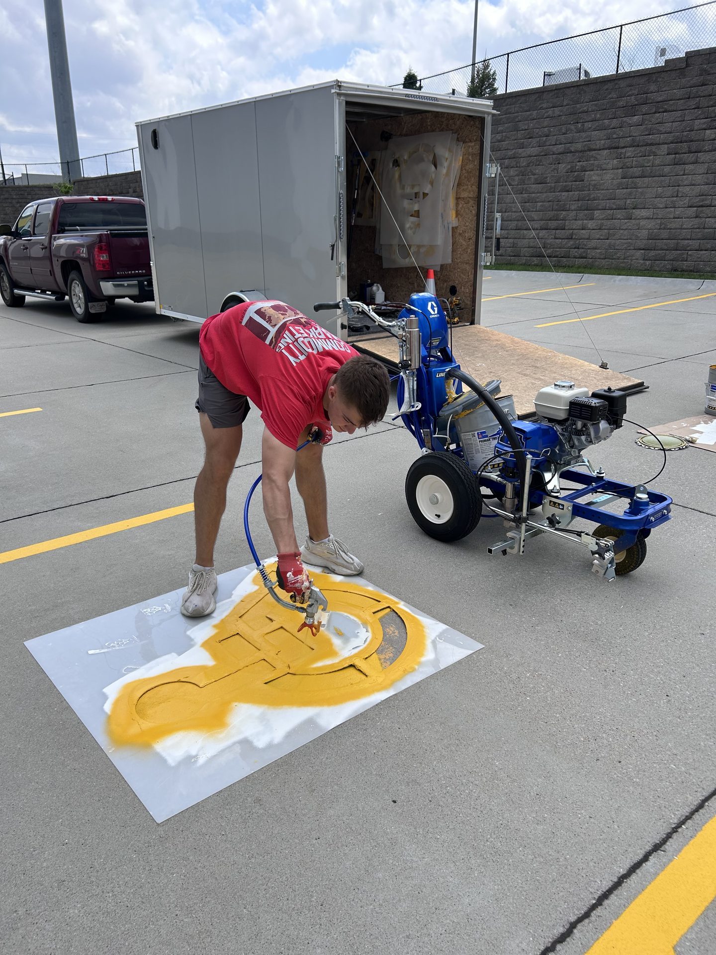 Karter Otte painting a stencil on pavement with a line striping machine