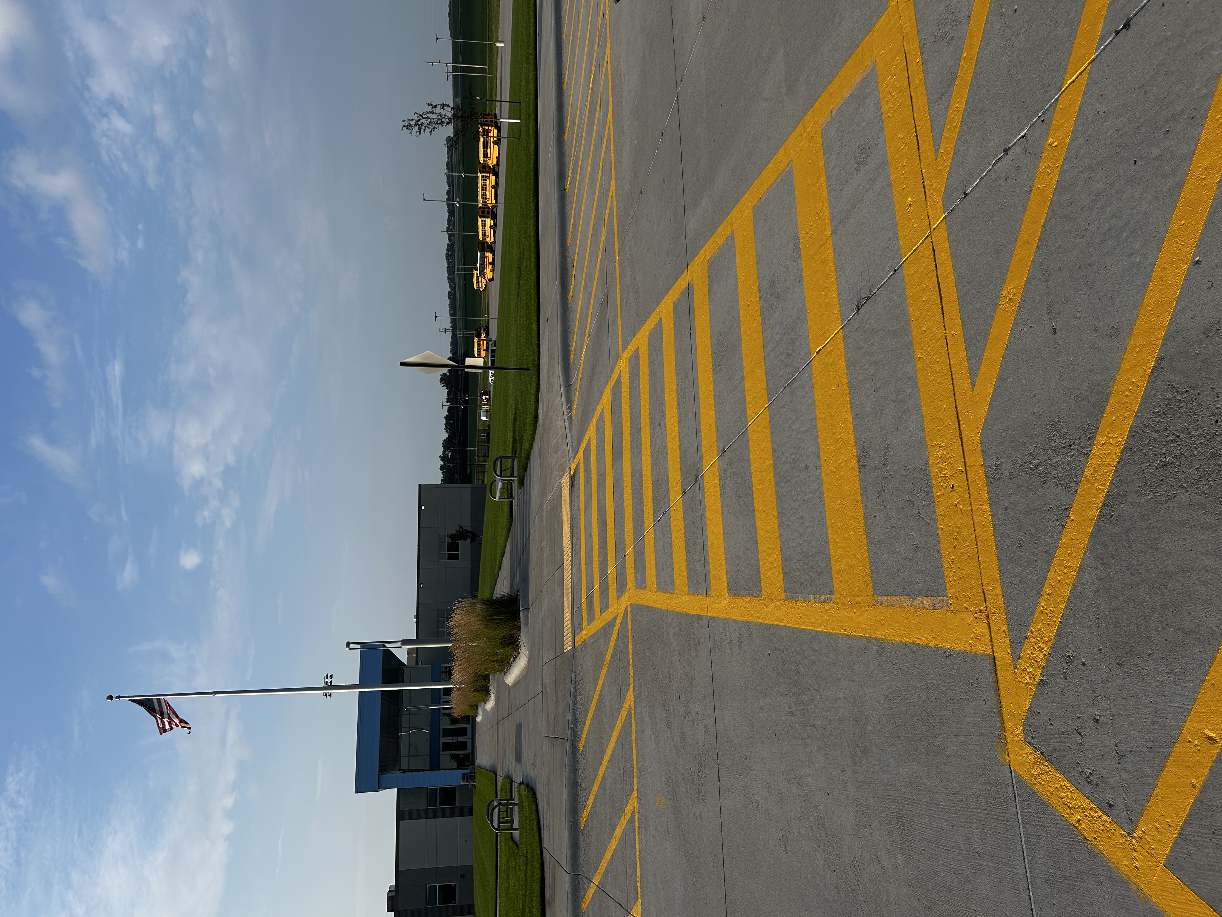School parking lot crosswalk striping with American flag and school buses