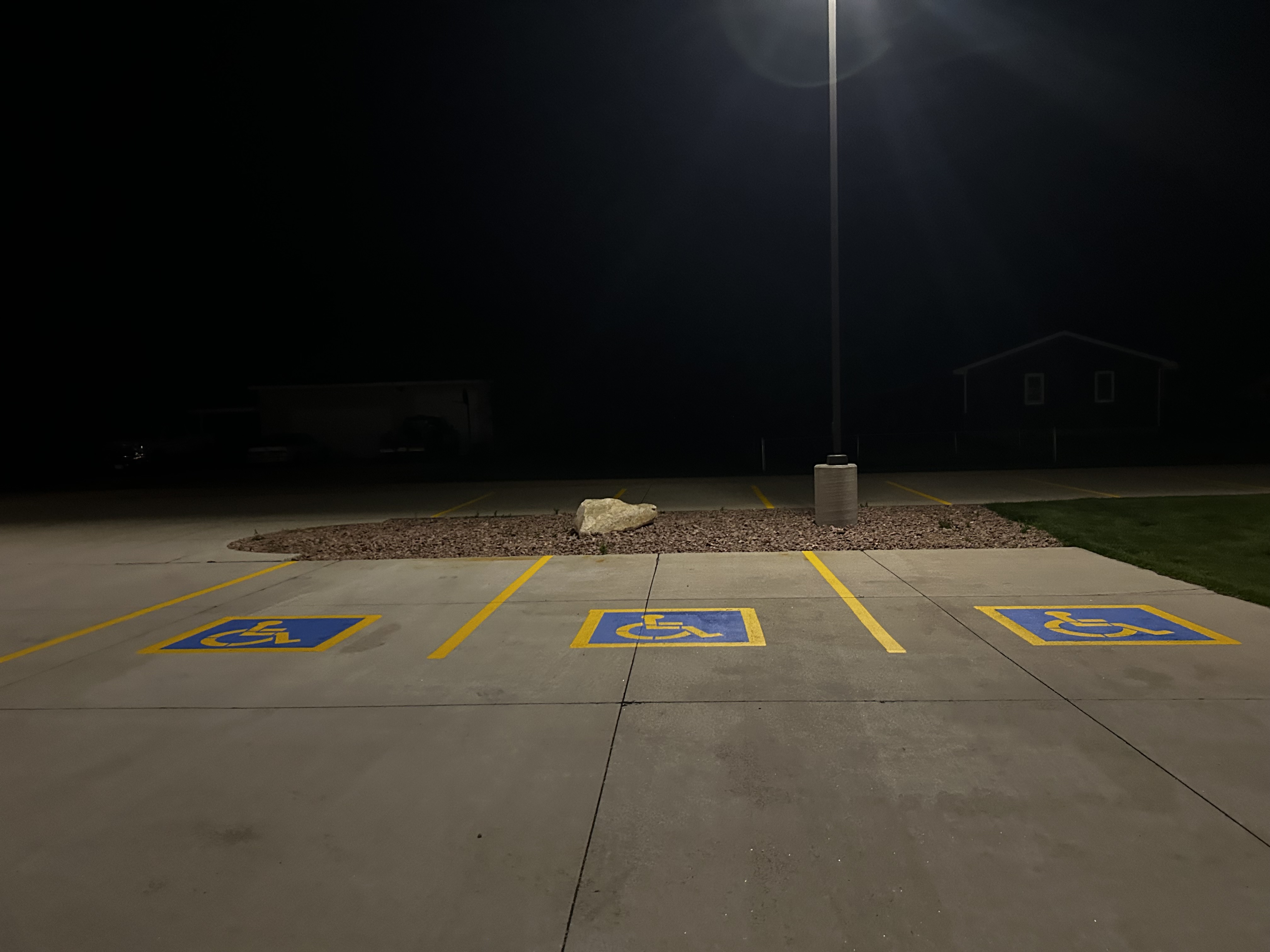 Night ADA handicap parking with yellow lines and landscaping rocks