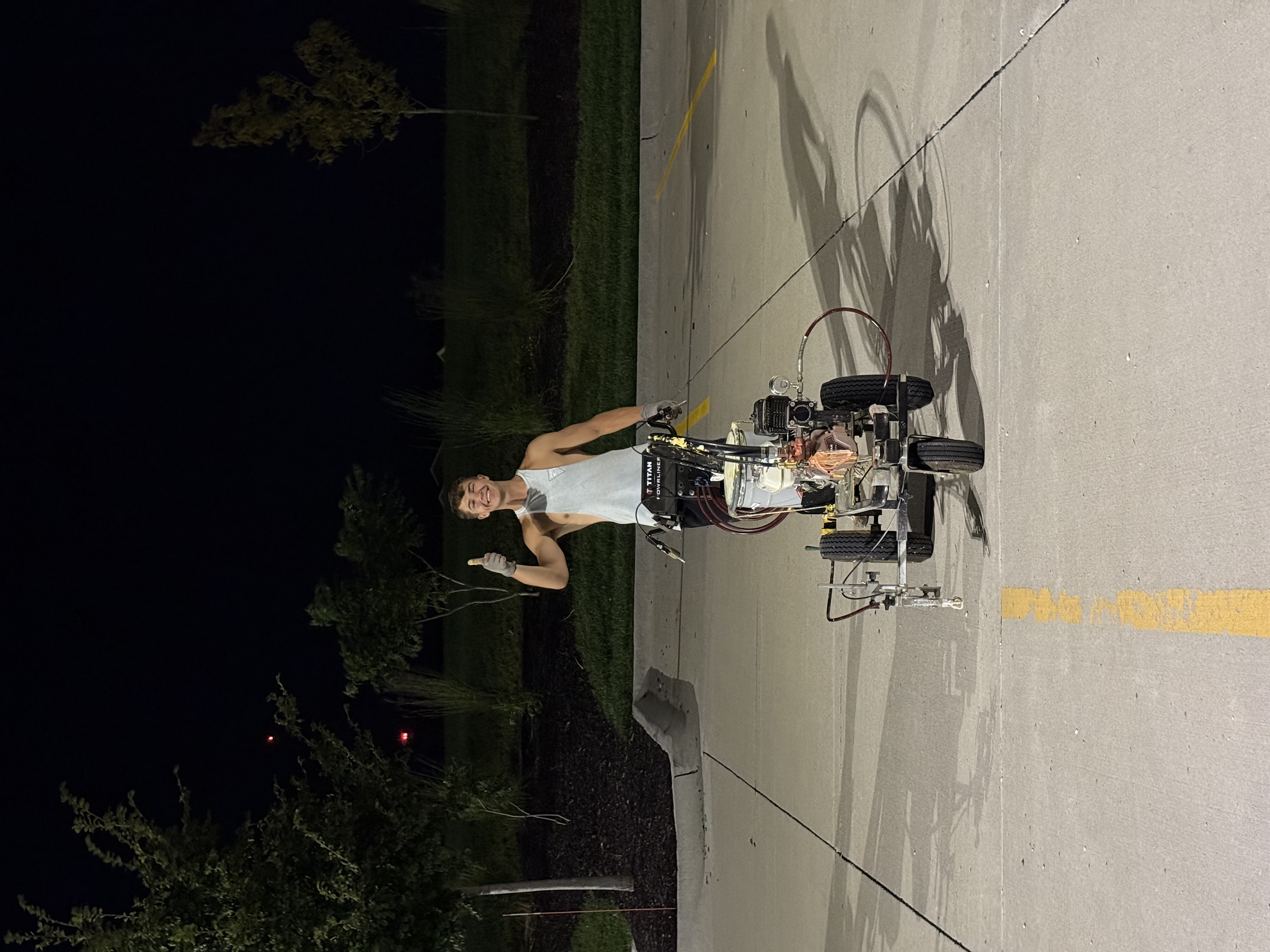 Karter Otte with line striping equipment giving thumbs up at night