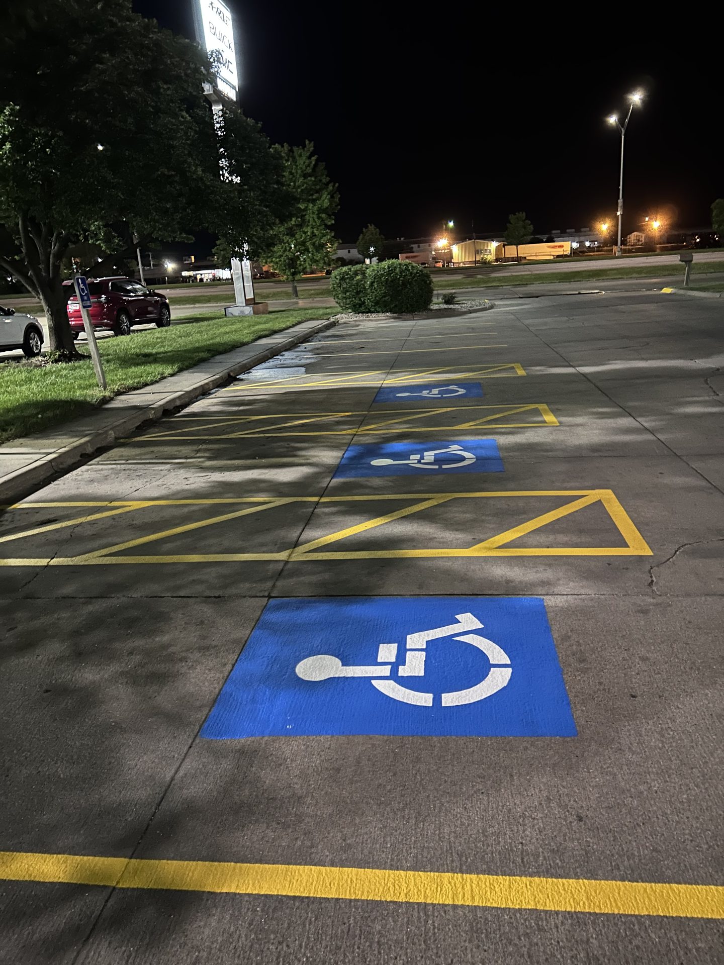 Freshly striped ADA stalls with blue symbols under parking lot lights at night